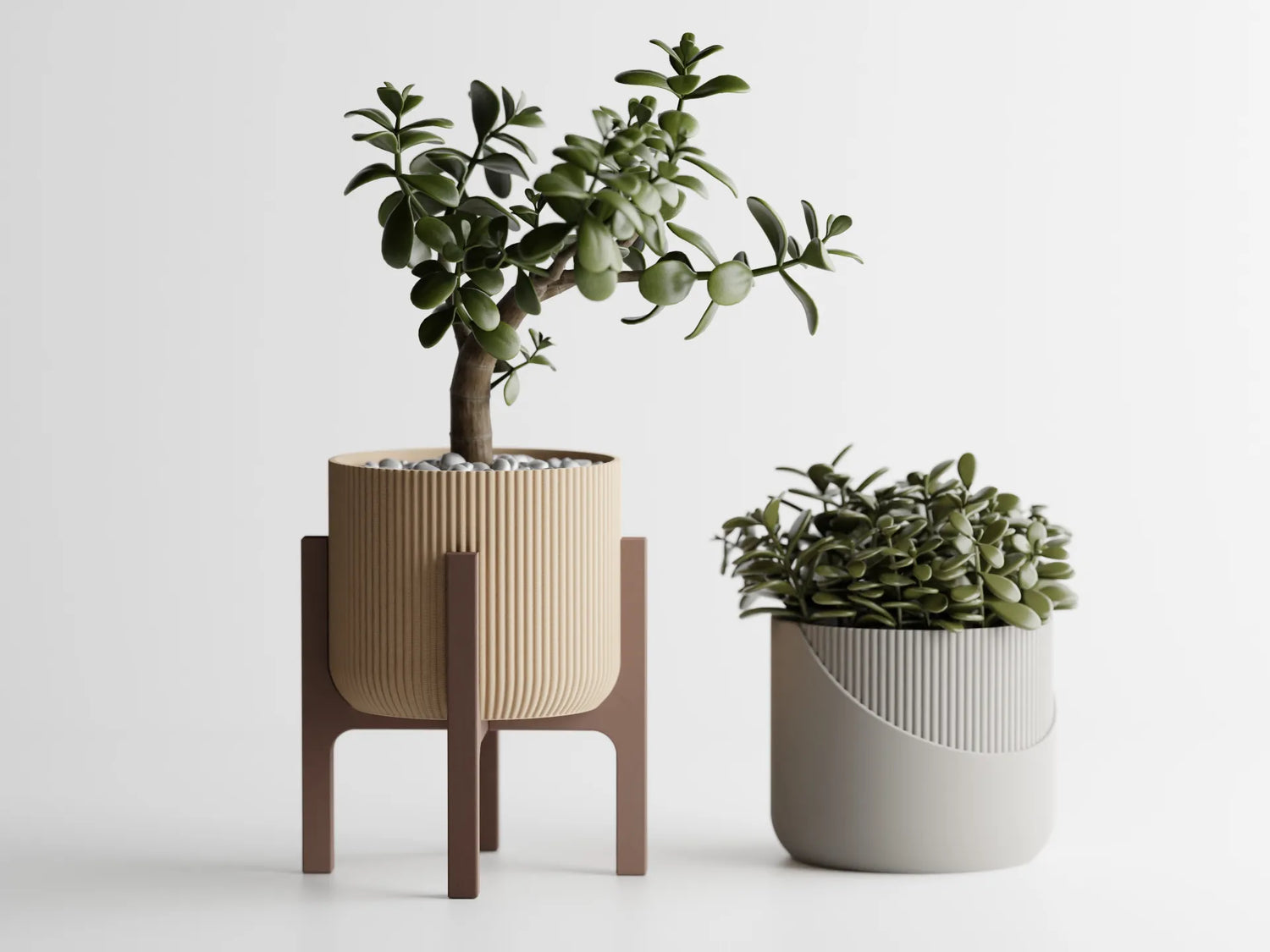 Two green potted plants in contemporary 3D printed planters, one raised on a wooden stand and the other in a rounded vessel with ribbed detailing, set against a white background