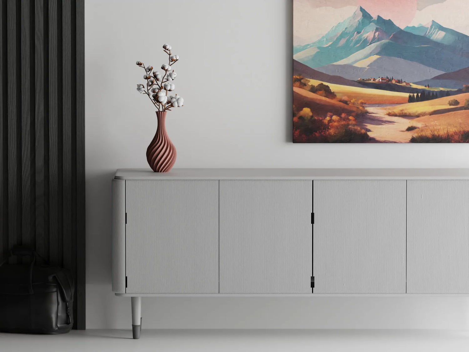 Terracotta spiral 3D printed vase with cotton stems on a modern grey cabinet, set beneath a colorful mountain landscape painting on a white wall